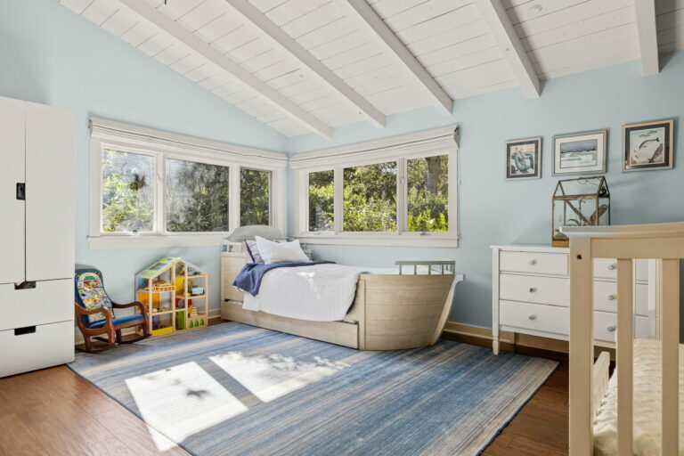 A boy's room with blue walls and white furniture.