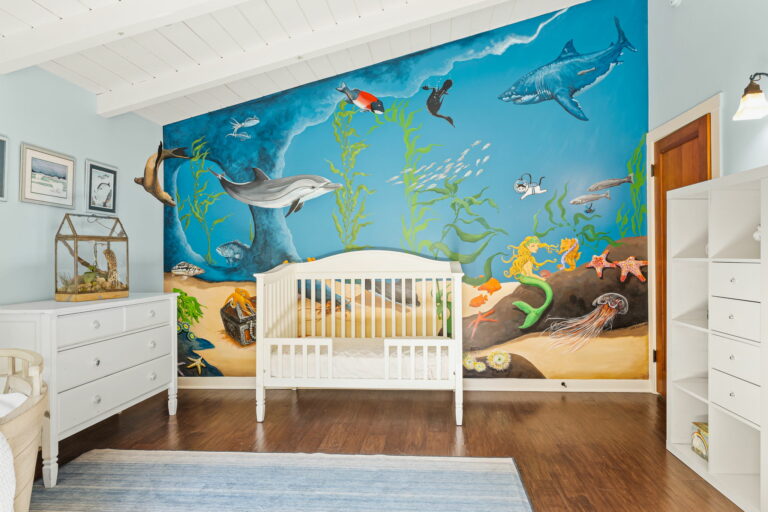 A baby's room with a crib, dresser, and a mural.