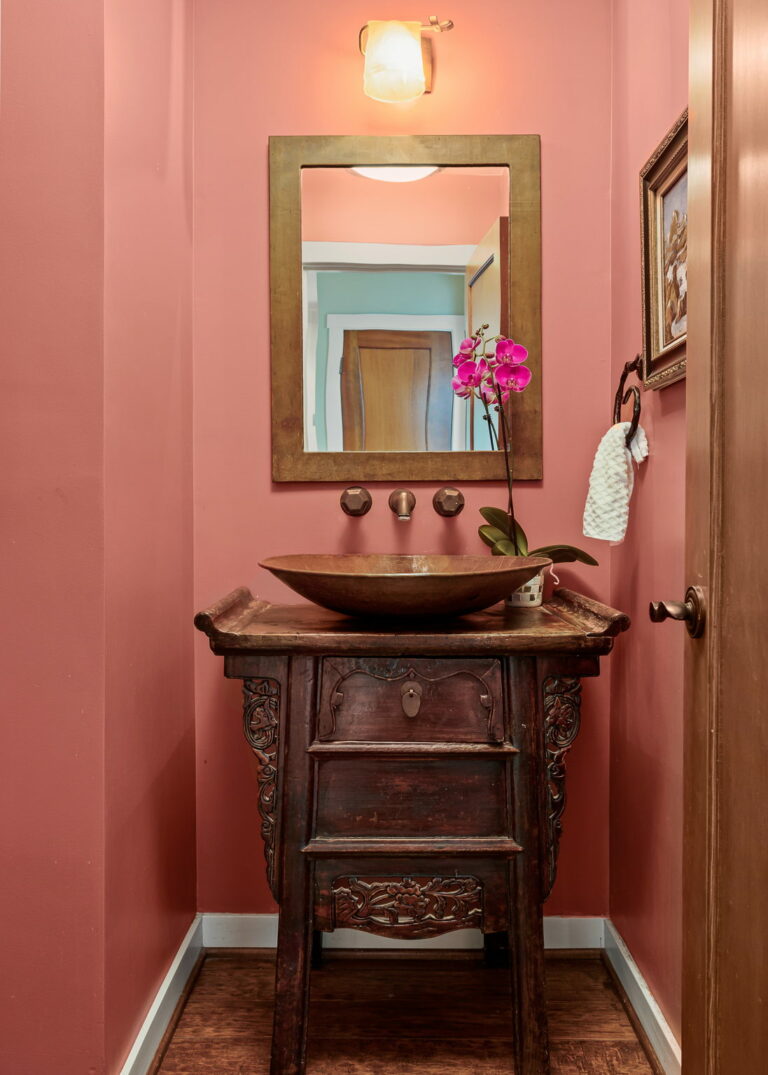 A bathroom with pink walls and a wooden vanity.