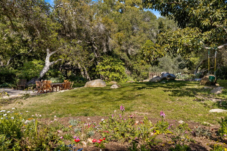 A garden with trees and flowers in the background.