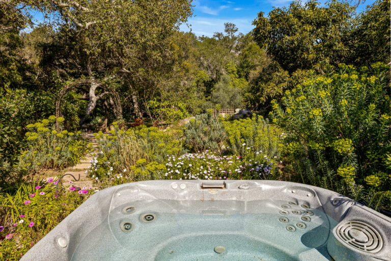 A hot tub sits in the middle of a garden.