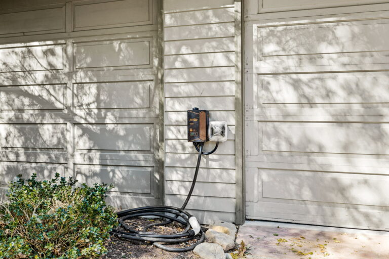 An electric car charger on the side of a house.