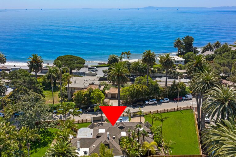 An aerial view of a house with a red arrow pointing to the ocean.