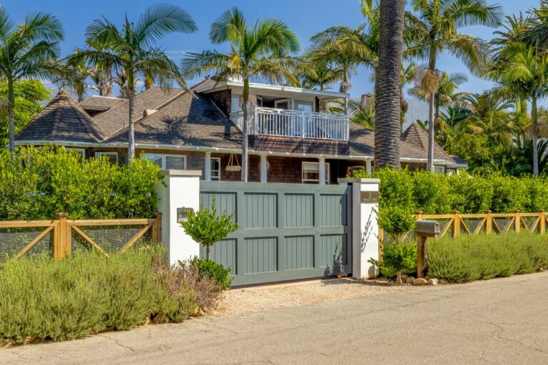 A home with a wooden gate and palm trees.