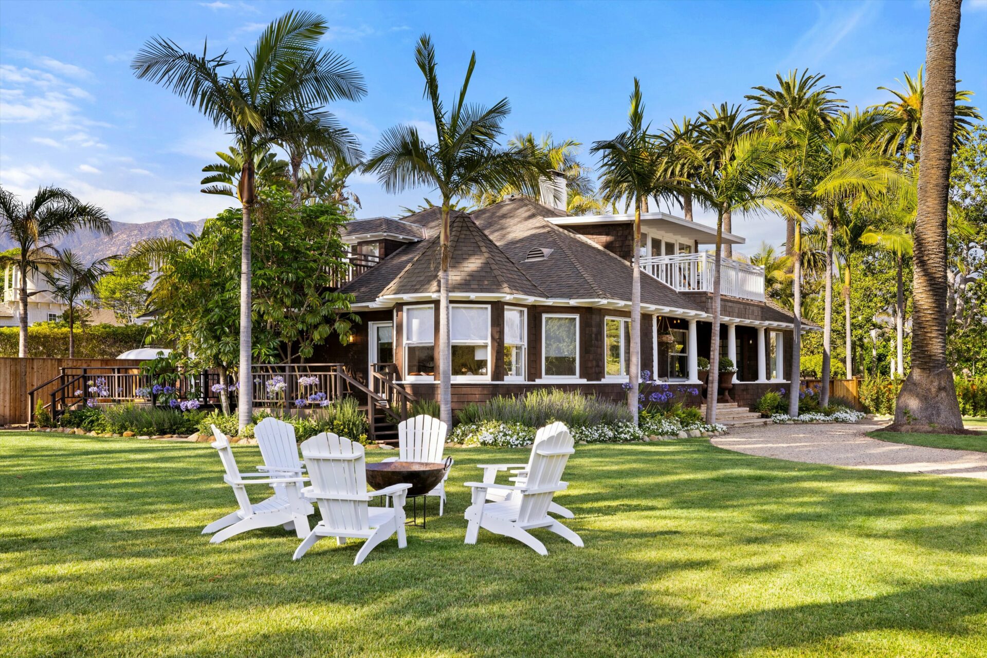 Luxury house with a landscaped garden and adirondack chairs on the lawn.