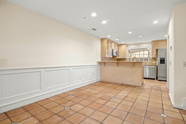 An empty kitchen with tile floors and wooden cabinets.