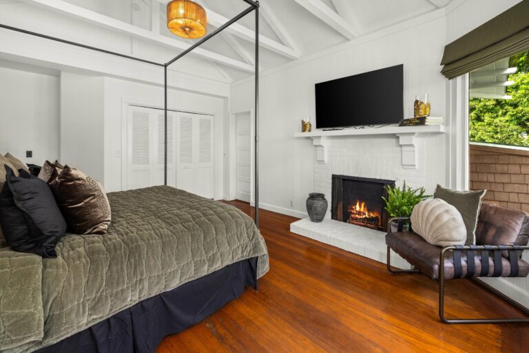 A bedroom with hardwood floors and a fireplace.