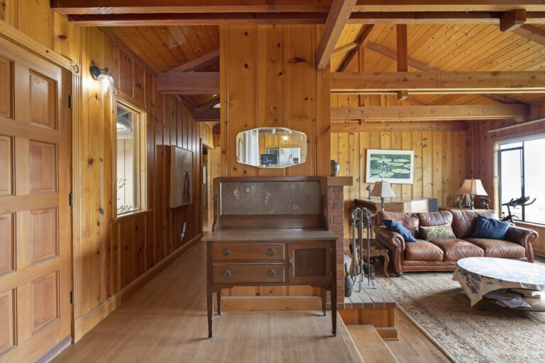 A living room with wood paneling and a dresser.
