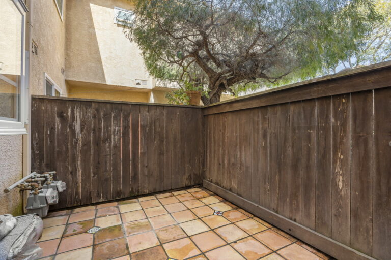 A small backyard with a wooden fence and a tree.
