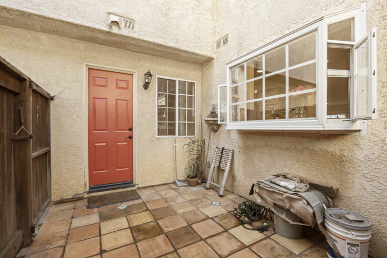 A tiled patio with a red door.