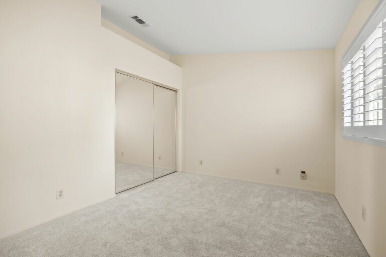 An empty room with a closet and a sliding door.