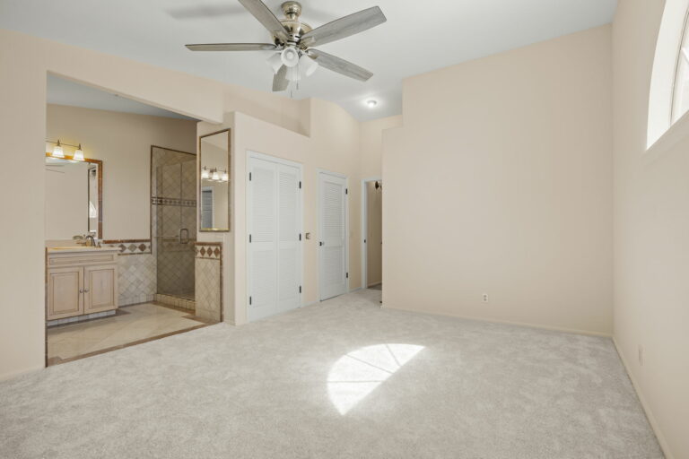 A room with a ceiling fan and carpet.
