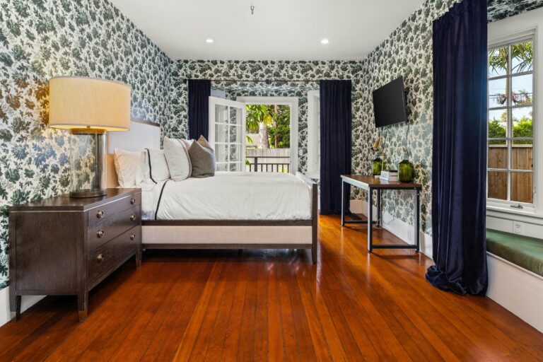 A bedroom with floral wallpaper and hardwood floors.