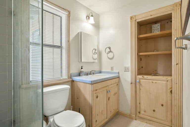 A bathroom with wooden cabinets and a toilet.