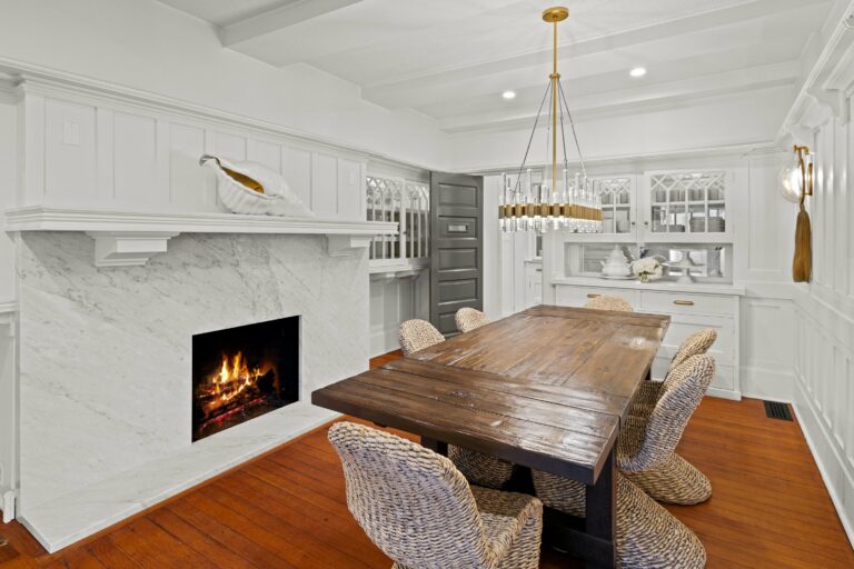 A white dining room with a fireplace and chairs.